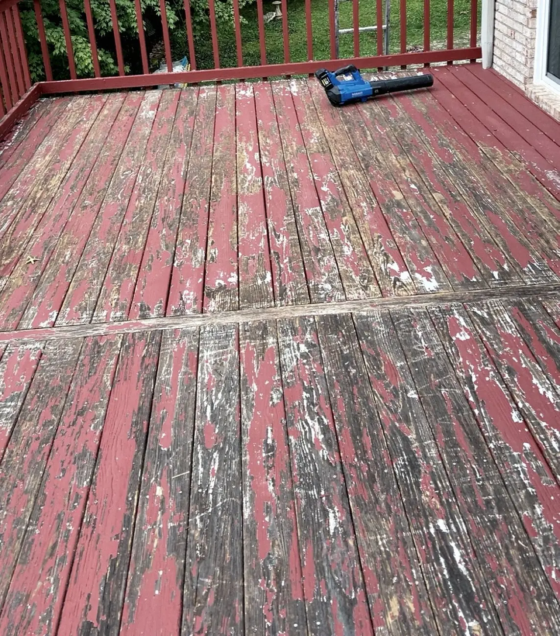 Before: red-painted deck boards with paint peeling off, a cordless blower lying on the deck.